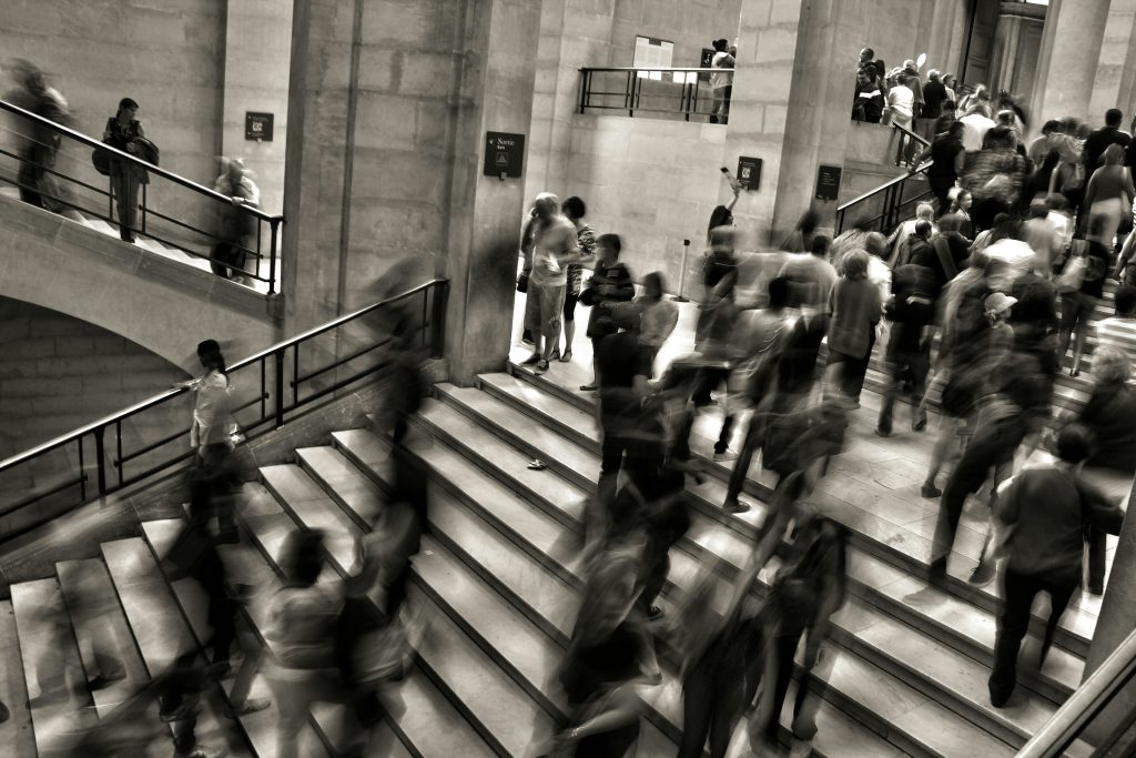 People moving along a busy stairway, in black and white
