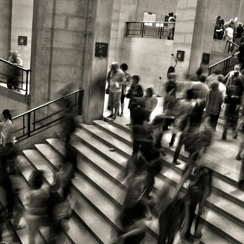 People moving along a busy stairway, in black and white