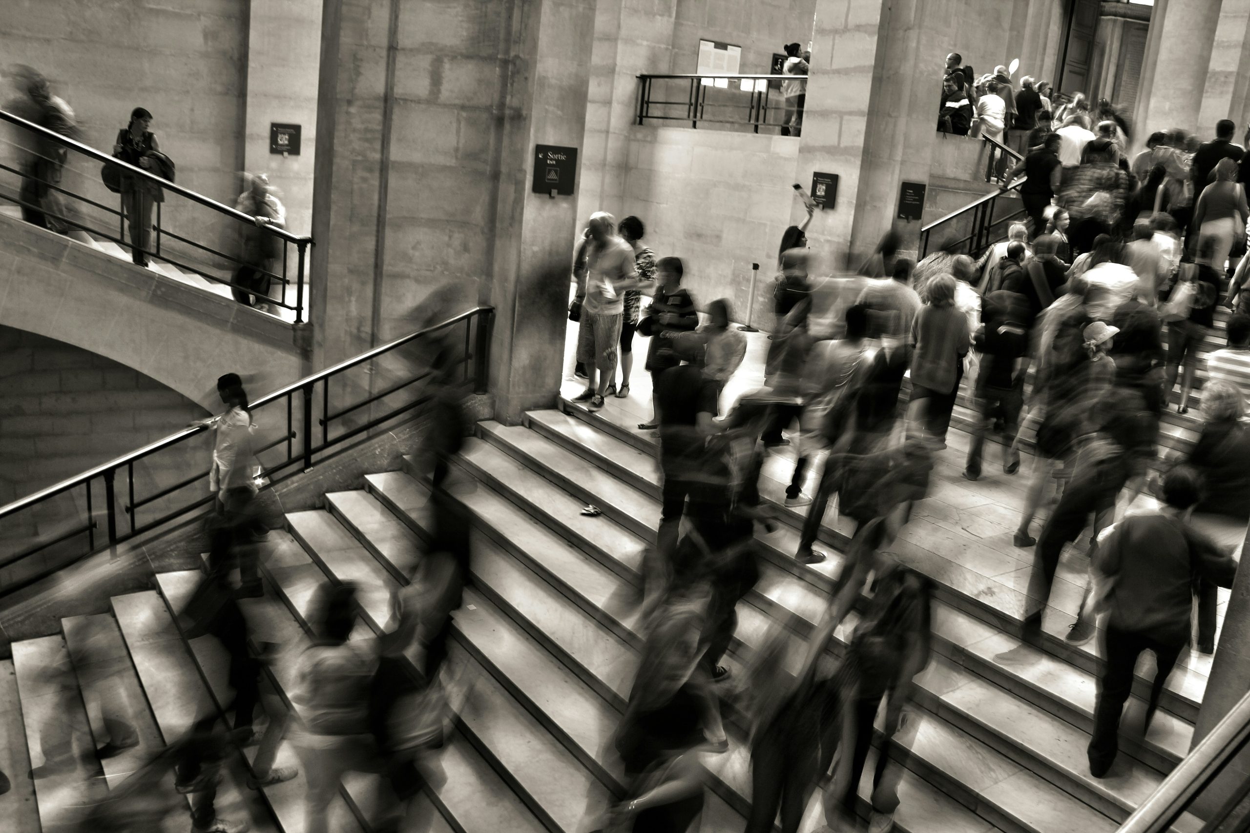 People moving along a busy stairway, in black and white